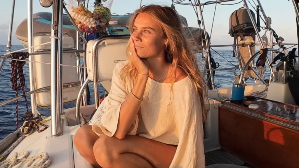 Lauren Landers sitting aboard her sailboat at sunset