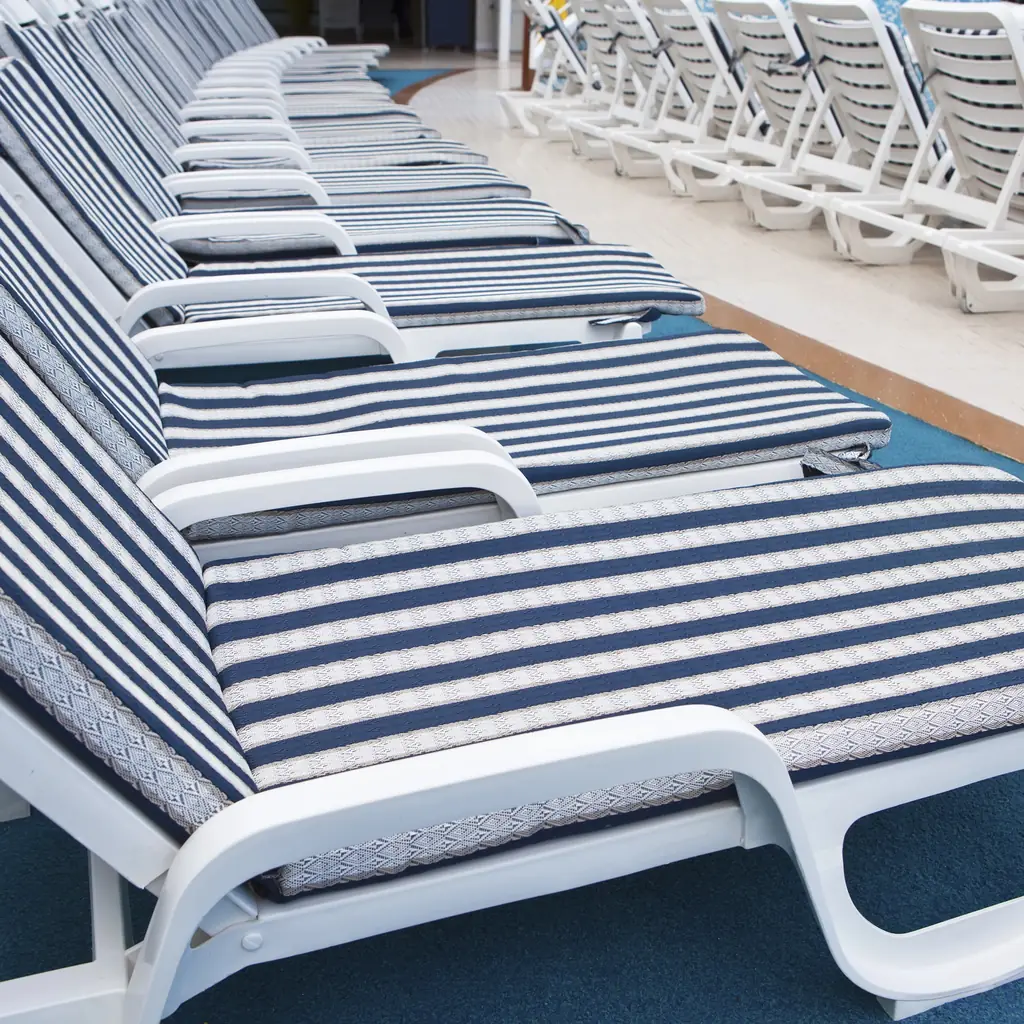 Rows of empty sun loungers on a cruise ship pool deck at dawn