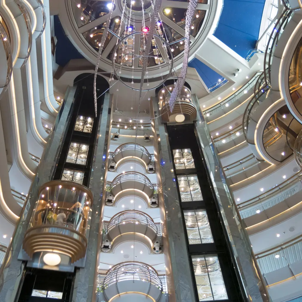 Glass elevators rising through a multi-deck cruise ship atrium