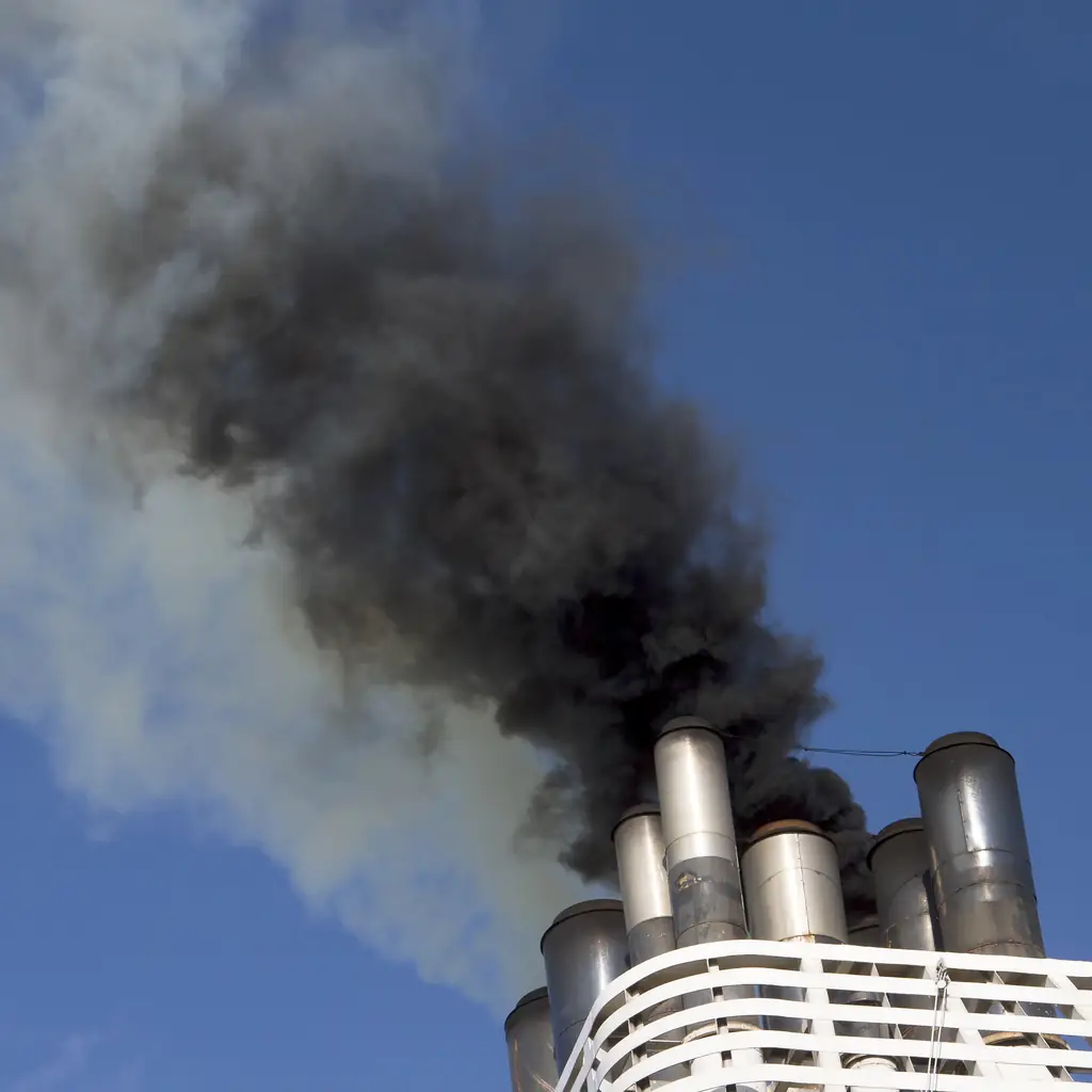 A cruise ship funnel with exhaust against the sky