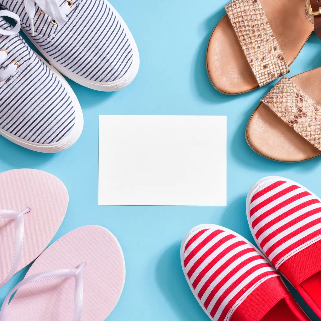 Canvas sneakers, sandals and flip-flops laid out on a blue background