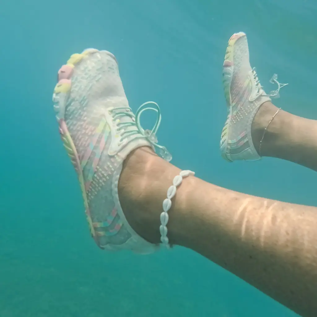 Feet in water shoes swimming in clear sea water