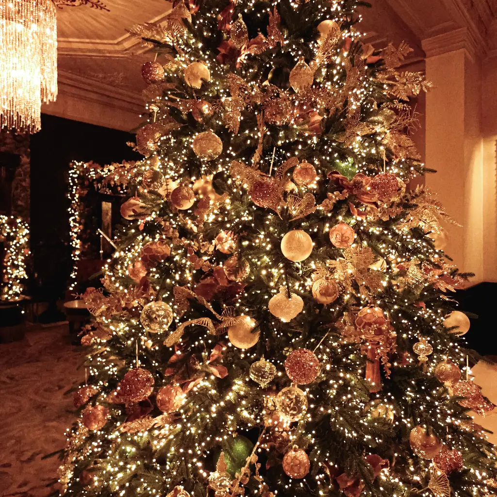 A tall lit Christmas tree in a grand lobby