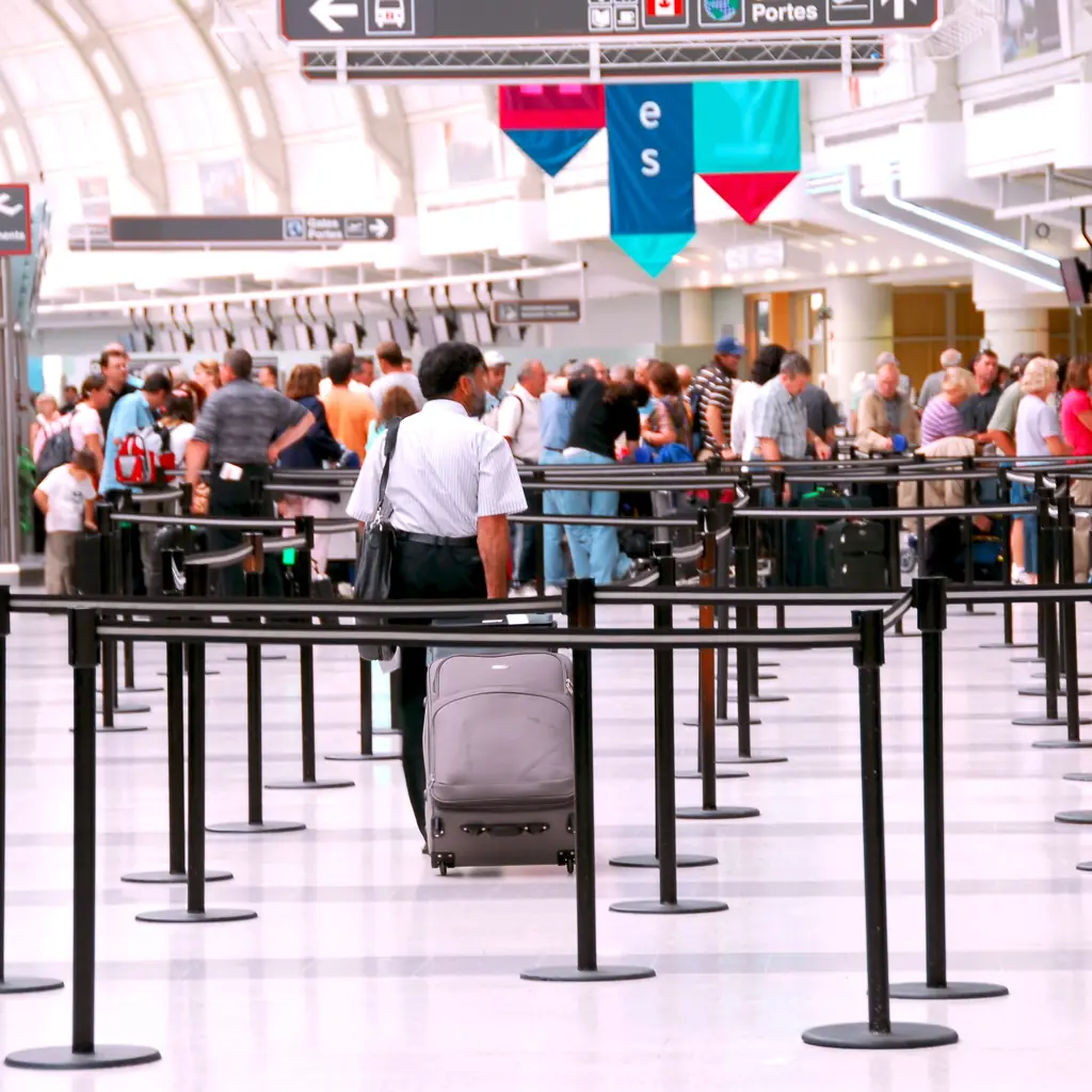A crowded airport hall with long queue lanes on a busy travel day