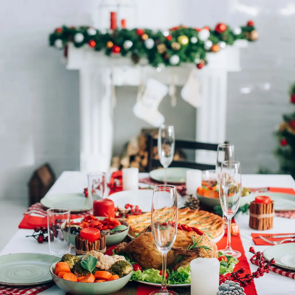 A home kitchen table set for a holiday dinner with candles and a roast, warm light