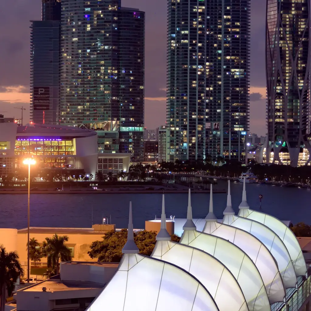 The Miami cruise terminal lit up at night below the downtown skyline
