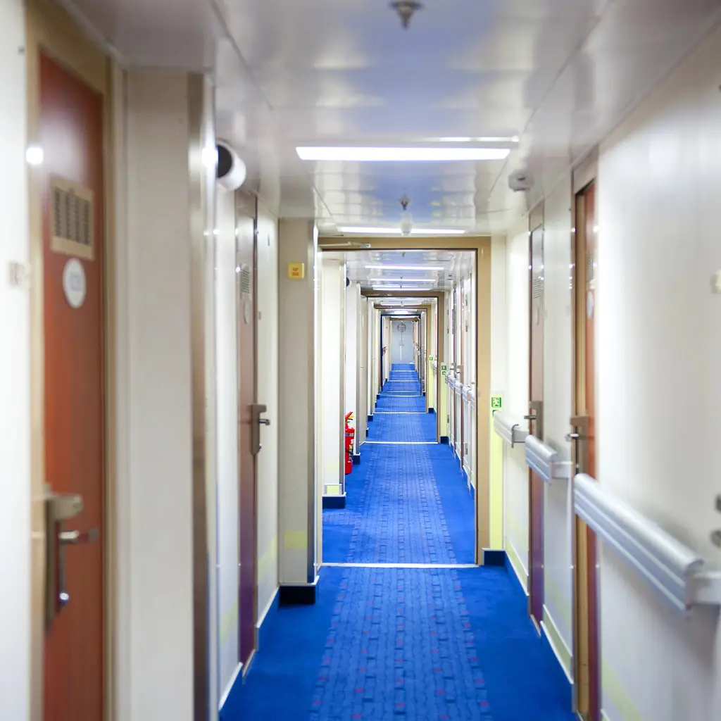Long cruise ship corridor with rows of cabin doors on both sides
