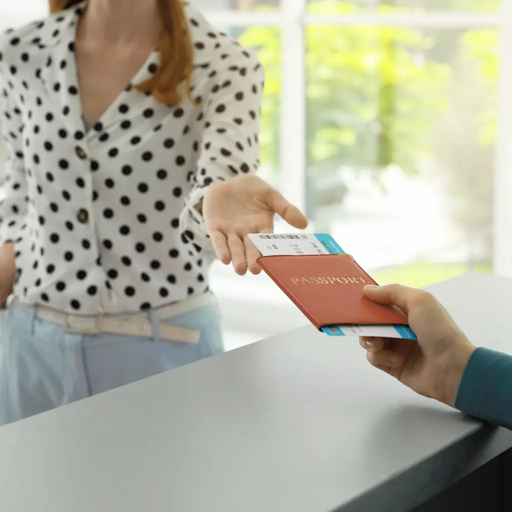 A traveler handing a passport and ticket across a check-in counter