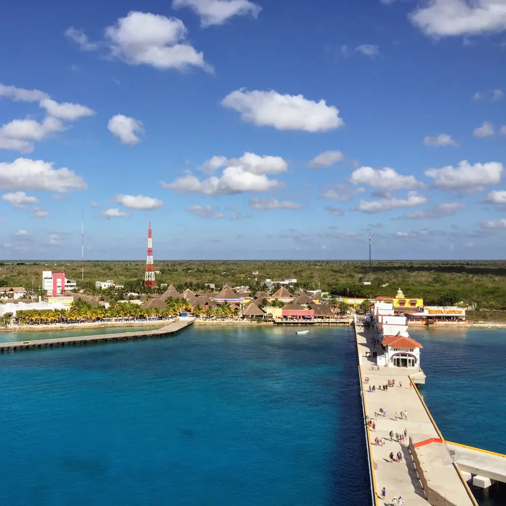 Cruise ship docked at a long pier in Cozumel, Mexico, over turquoise water
