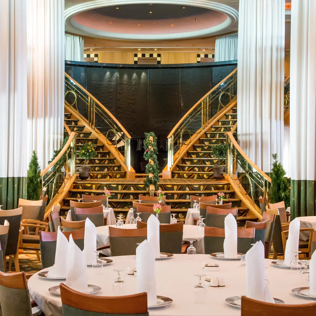 Cruise ship main dining room with tables set for dinner before guests arrive