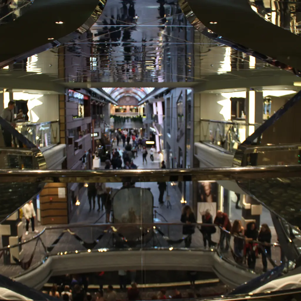 A multi-deck promenade inside a large cruise ship, seen from above