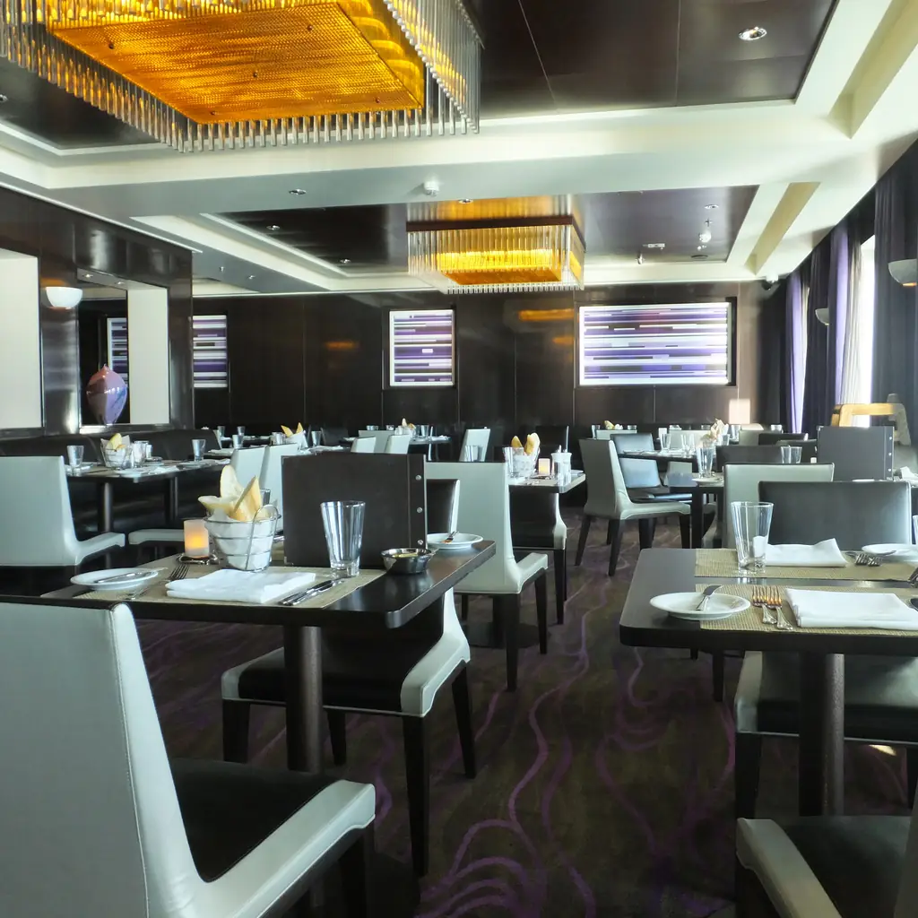 Empty cruise ship main dining room with tables set for dinner before passengers arrive