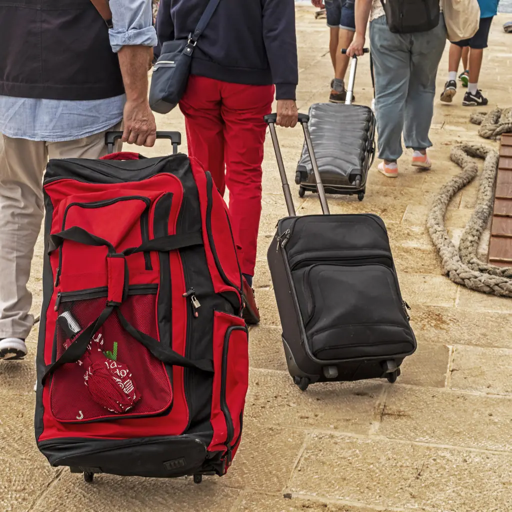 Passengers wheeling luggage along the quay on boarding day