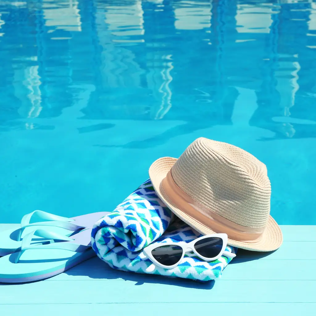 Flip-flops, a sun hat, sunglasses and a towel left at the pool edge