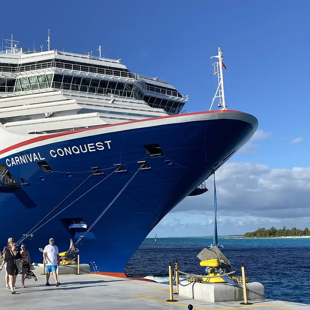 A Carnival Cruise Line ship with its winged funnel docked at a cruise port