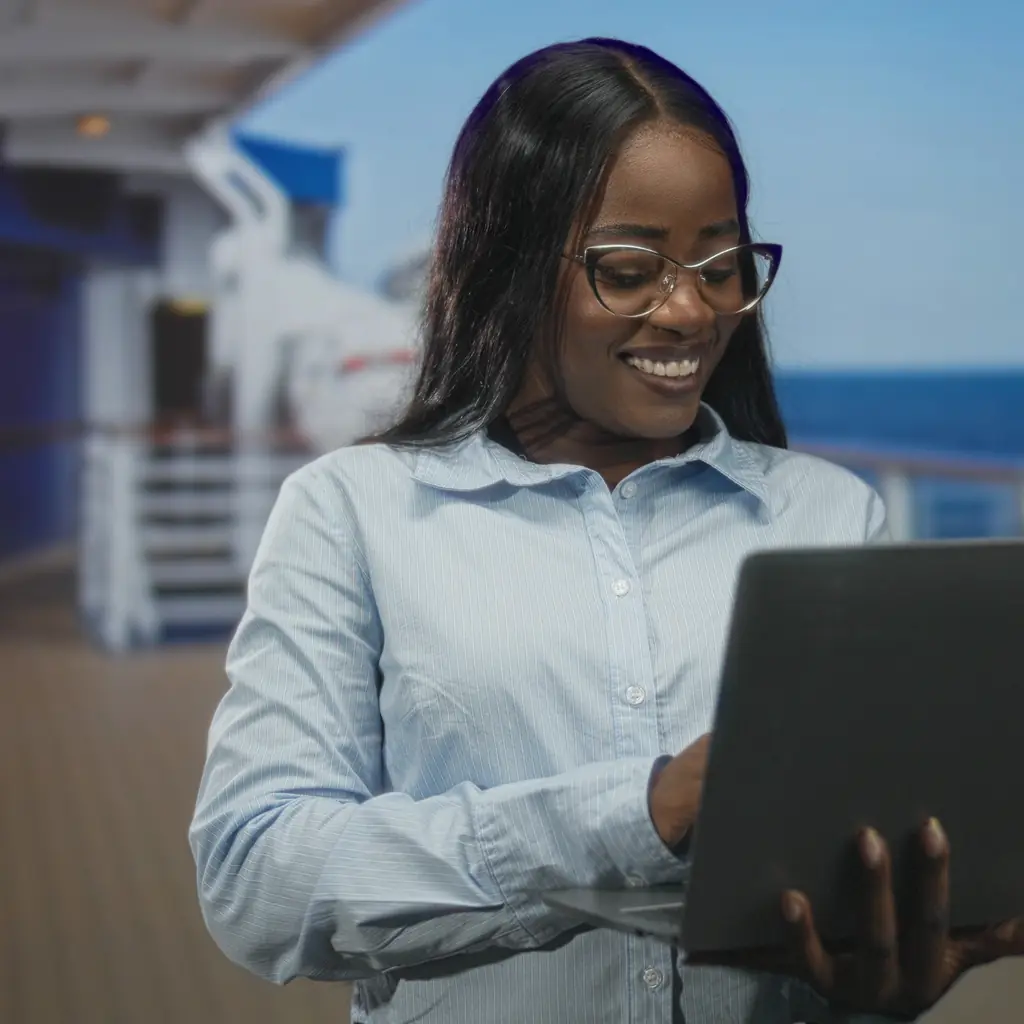 A passenger using a laptop on a cruise ship balcony with the sea behind