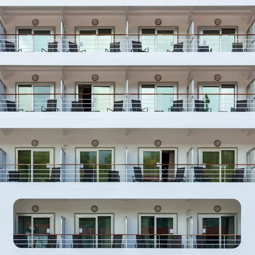 Rows of balcony staterooms along the side of a cruise ship in daylight