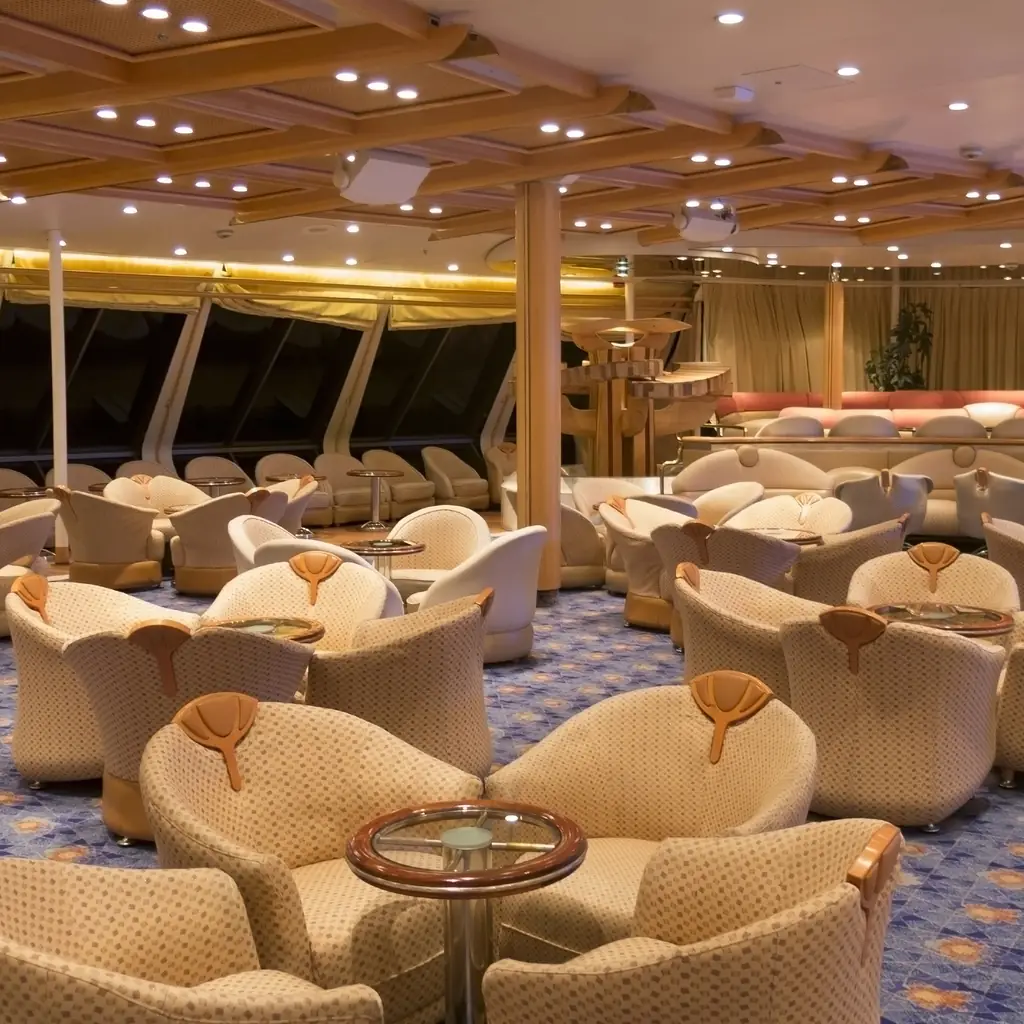 An upscale cruise ship lounge with armchairs and large windows looking out to sea