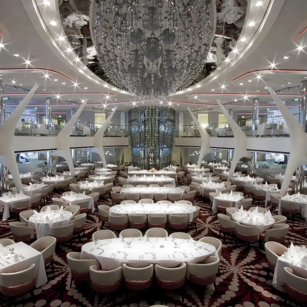 A two-deck cruise ship main dining room set for dinner