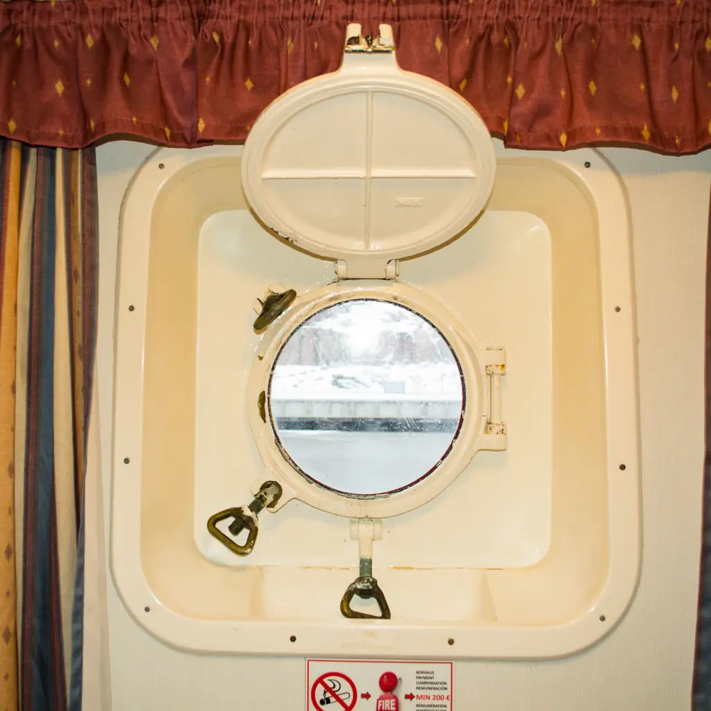 A sealed porthole window in a cruise oceanview cabin, showing the ocean view without outdoor balcony access.