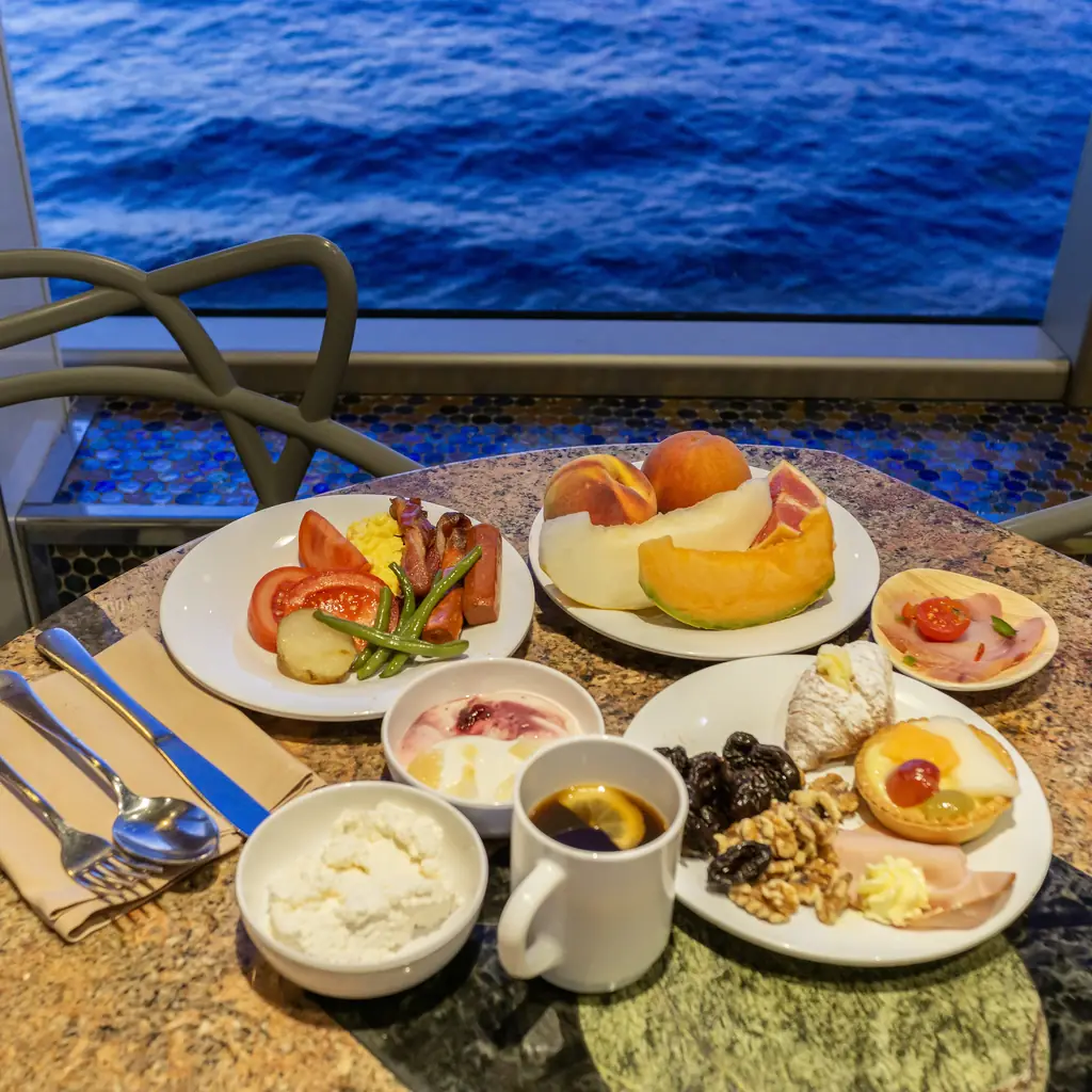 A breakfast spread served table-side on a cruise ship balcony, the kind of in-suite service a butler or concierge can arrange.